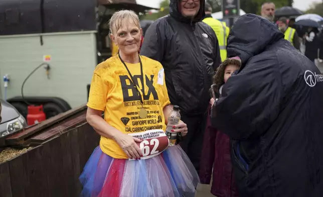 A competitor takes a drink after finishing her run in the World Coal Carrying Championships in Ossett, West Yorkshire, England, Monday, April 21, 2025. (AP Photo/Jon Super)