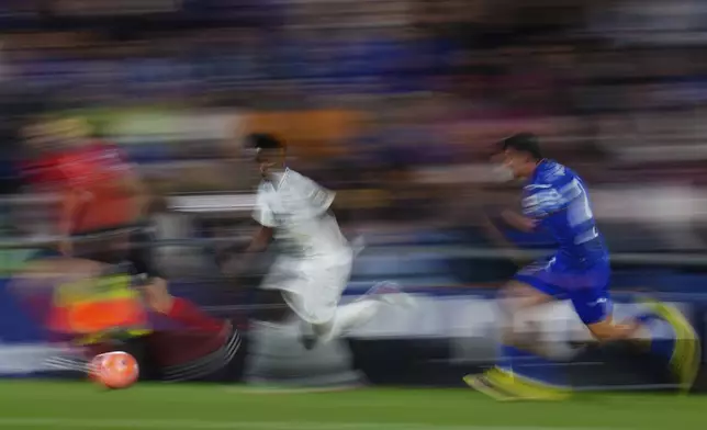 Real Madrid's Vinicius Junior, left, and Getafe's Juan Iglesias challenge for the ball during a Spanish La Liga soccer match between Getafe and Real Madrid at the Coliseum Alfonso Perez stadium in Getafe, Spain, Wednesday, April 23, 2025. (AP Photo/Manu Fernandez)
