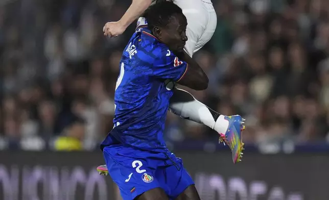 Getafe's Djene Dakonam, bottom, and Real Madrid's Fran Garcia challenge for the ball during a Spanish La Liga soccer match between Getafe and Real Madrid at the Coliseum Alfonso Perez stadium in Getafe, Spain, Wednesday, April 23, 2025. (AP Photo/Manu Fernandez)