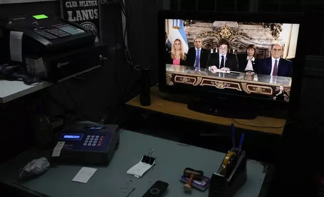 A television screen in a car garage displays a national address by President Javier Milei, accompanied by Cabinet members, in Buenos Aires, Argentina, Friday, April 11, 2025. (AP Photo/Natacha Pisarenko)