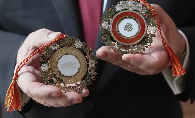 White House Historical Association President Stewart McLaurin poses with the 2025 White House Christmas ornament, seen at front and back, Thursday, April 10, 2025, at the association in Washington. (AP Photo/Jacquelyn Martin)