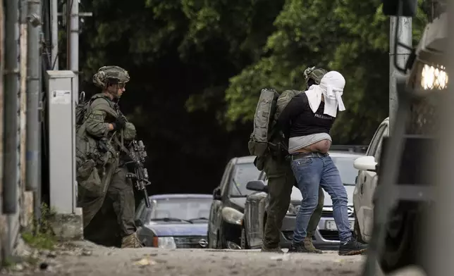 Israeli soldiers arrest a blindfolded Palestinian during an army raid in Nablus, West Bank, on Tuesday, April 8, 2025. (AP Photo/Majdi Mohammed)