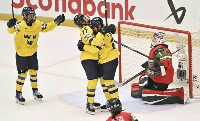 Sweden's, from left, Hilda Svensson, Linnea Johansson and Lina Ljungblom celebrate a goal past Hungary's goalkeeper Anikó Németh during a Group B match at the women's ice hockey world championships, Thursday, April 10, 2025, in Ceske Budejovice, Czech Republic. (Lubos Pavlicek/CTK via AP)