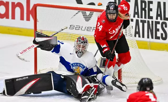 Finland goalkeeper Emilia Kyrkkö and Canada's Natalie Spooner battle for the puck during a Group A match at the women's ice hockey world championships, Thursday, April 10, 2025, in Ceske Budejovice, Czech Republic. (Vaclav Pancer/CTK via AP)
