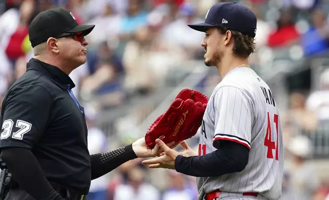 Minnesota Twins pitcher Joe Ryan (41) has his glove checked by umpire Carlos Torres (37) during the third inning of a baseball game against the Minnesota Twins, Saturday, April 20, 2025, in Atlanta. (AP Photo/John David Mercer)