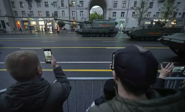 People watch military vehicles driving along Tverskaya street toward Red Square to attend a rehearsal for the Victory Day military parade in Moscow, Russia, on Tuesday, April 29, 2025. (AP Photo/Pavel Bednyakov)