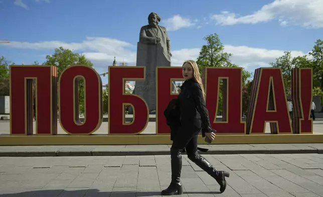 A woman walks next to an installation reading "Victory" In Russian, installed next to the monument of Karl Marx ahead of celebrations of the 80th anniversary of the Soviet Union's victory over Nazi Germany during World War II, in Moscow, Russia, Monday, April 28, 2025. (AP Photo/Pavel Bednyakov)