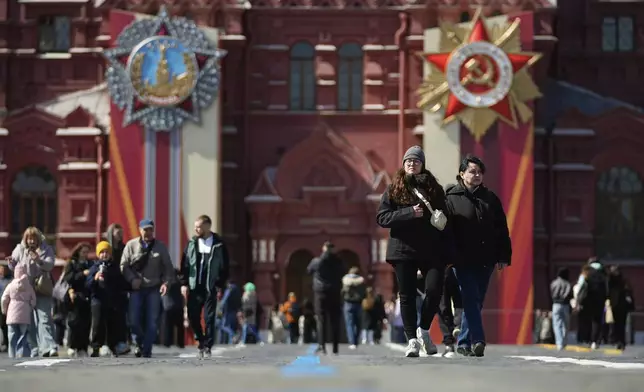 People walk along the Red Square with the Order of Victory and the Order of the Patriotic War in the background ahead of celebrations of the 80th anniversary of the Soviet Union's victory over Nazi Germany during World War II, in Moscow, Russia, Monday, April 28, 2025. (AP Photo/Pavel Bednyakov)