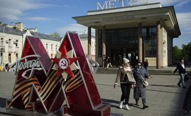 People walk next to a Moscow subway logo decorated with the word "Victory" in Russian and the Order of the Patriotic War, installed next to Chistye Prudy subway station entrance ahead of celebrations of the 80th anniversary of the Soviet Union's victory over Nazi Germany during World War II, in Moscow, Russia, Monday, April 28, 2025. (AP Photo/Pavel Bednyakov)