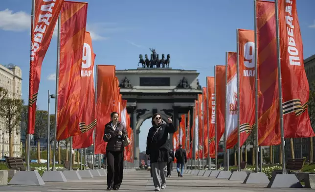 People walk along flags reading "May 9" and "Victory" in Russian, installed at the Victory Square next to the Triumphal Arch, ahead of celebrations of the 80th anniversary of the Soviet Union's victory over Nazi Germany during World War II, in Moscow, Russia, Monday, April 28, 2025. (AP Photo/Pavel Bednyakov)