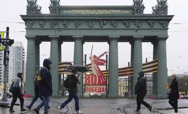 People cross a street in St. Petersburg, Russia, on Monday, April 28, 2025, in front of what is known as the Moscow Triumphal Gate, ahead of next week's celebration of the 80th anniversary of the Soviet Union's victory over Nazi Germany during World War II. (AP Photo/Dmitri Lovetsky)
