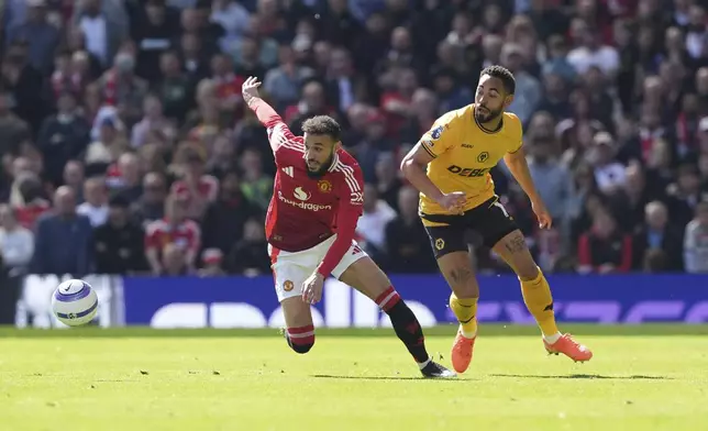Manchester United's Noussair Mazraoui, left and Wolverhampton Wanderers' Matheus Cunha vie for the ball, during the English Premier League soccer match between Manchester United and Wolverhampton Wanderers, at Old Trafford, Manchester, England, Sunday, April 20, 2025. (Martin Rickett/PA via AP)