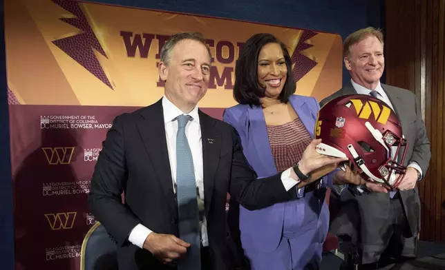 Washington Commanders controlling owner Josh Harris, from left, District of Columbia Mayor Muriel Bowser and NFL Commissioner Roger Goodell hold up a signed helmet after an announcement about a new home for the NFL football team on the site of the old RFK Stadium, Monday, April 28, 2025, at the National Press Club in Washington. (AP Photo/Jacquelyn Martin)