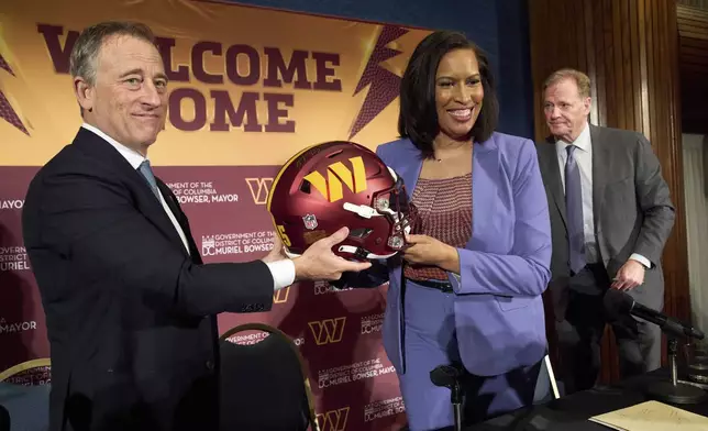 Washington Commanders controlling owner Josh Harris, from left, holds up a signed helmet along with District of Columbia Mayor Muriel Bowser and NFL Commissioner Roger Goodell after an announcement about a new home for the NFL football team on the site of the old RFK Stadium, Monday, April 28, 2025, at the National Press Club in Washington. (AP Photo/Jacquelyn Martin)
