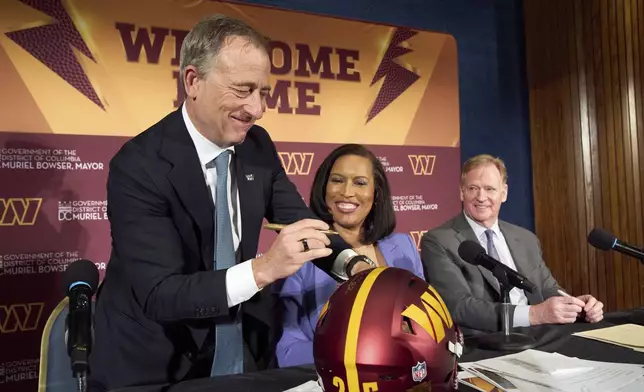 Washington Commanders controlling owner Josh Harris, from left, signs a helmet along with District of Columbia Mayor Muriel Bowser and NFL Commissioner Roger Goodell after an announcement about a new home for the NFL football team on the site of the old RFK Stadium, Monday, April 28, 2025, at the National Press Club in Washington. (AP Photo/Jacquelyn Martin)