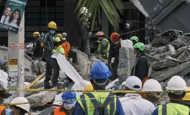 Rescue workers use sheets as they recover bodies from the rubble at the Jet Set nightclub after its roof collapsed two nights prior during a merengue concert in Santo Domingo, Dominican Republic, Wednesday, April 9, 2025. (AP Photo/Ricardo Hernandez)