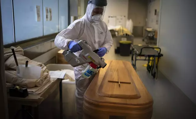 FILE - A mortuary worker disinfests a coffin carrying the body of a person who died of COVID-19 ahead of a funeral at Memora mortuary in Girona, Spain, Thursday, Feb. 4, 2021. (AP Photo/Emilio Morenatti, File)