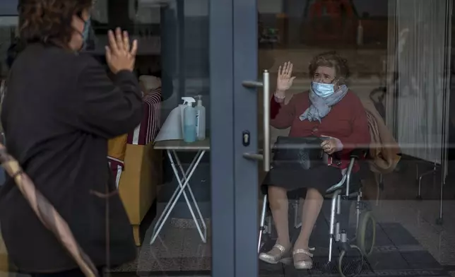 FILE -Angels Trepat, 59, says through a window goodbye to her mother Angelina, 91, after visiting her at the Icaria nursing home in Barcelona, Spain, Friday, Nov. 27, 2020. (AP Photo/Emilio Morenatti, File)