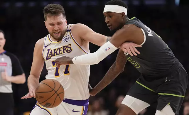 Minnesota Timberwolves forward Jaden McDaniels, right, reaches in on Los Angeles Lakers guard Luka Doncic during the first half in Game 1 of an NBA first-round playoff series Saturday, April 19, 2025, in Los Angeles. (AP Photo/Mark J. Terrill)
