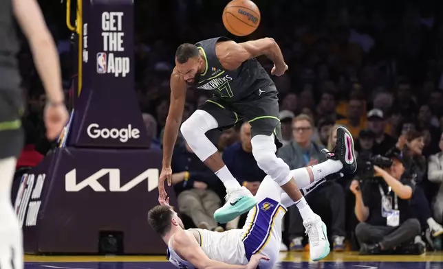 Minnesota Timberwolves center Rudy Gobert, top, trips over Los Angeles Lakers guard Luka Doncic during the first half in Game 1 of an NBA first-round playoff series Saturday, April 19, 2025, in Los Angeles. (AP Photo/Mark J. Terrill)