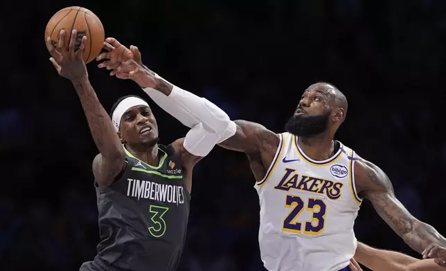Minnesota Timberwolves forward Jaden McDaniels, left, and Los Angeles Lakers forward LeBron James grapple for the ball during the first half in Game 1 of an NBA first-round playoff series Saturday, April 19, 2025, in Los Angeles. (AP Photo/Mark J. Terrill)