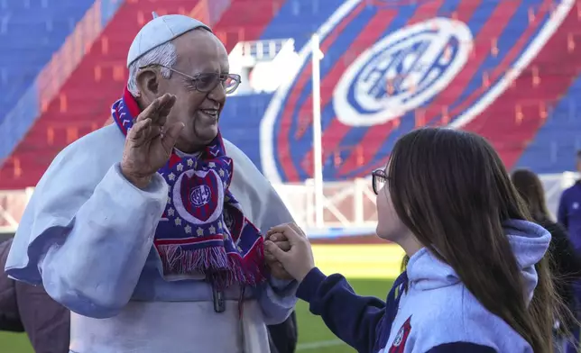 A San Lorenzo soccer fan touches a statue depicting the late Pope Francis, who was a lifelong supporter of the club, prior a local match against Rosario Central in Buenos Aires, Argentina, Saturday, April 26, 2025. (AP Photo/Gustavo Garello)