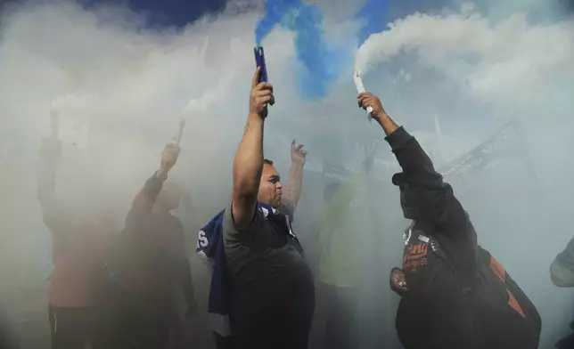 Mourners hold flares as they pay tribute to the late Pope Francis outside the Cathedral in Buenos Aires, Argentina, Saturday, April 26, 2025, on the day of his funeral in Rome. (AP Photo/Victor R. Caivano)