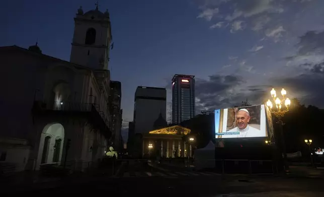 An image of the late Pope Francis is projected on a screen outside the Cathedral in Buenos Aires, Argentina, Saturday, April 26, 2025, as his funeral takes place in Rome. (AP Photo/Natacha Pisarenko)
