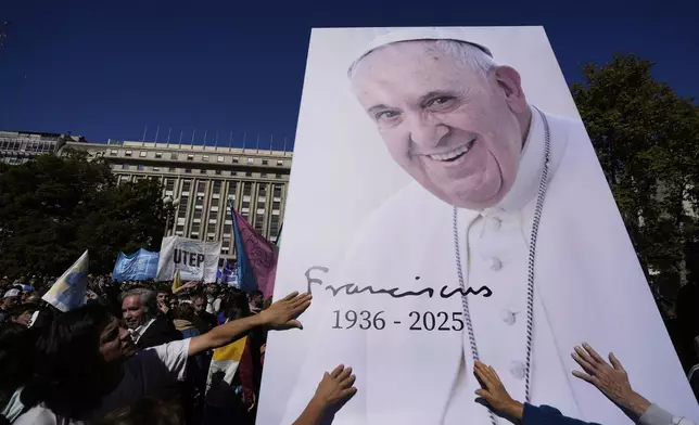 Mourners touch an image of the late Pope Francis outside the Cathedral in Buenos Aires, Argentina, Saturday, April 26, 2025, on the day of his funeral in Rome. (AP Photo/Natacha Pisarenko)
