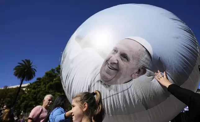 Mourners stand next to a balloon with the image of the late Pope Francis during a Mass outside the Cathedral in Buenos Aires, Argentina, Saturday, April 26, 2025, on the day of his funeral in Rome. (AP Photo/Natacha Pisarenko)