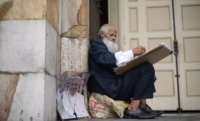 Oscar Gomez a street artist waits outside the Cathedral for a mass in tribute to the late Pope Francis in Bogota, Colombia, Saturday, April 26, 2025. (AP Photo/Fernando Vergara)