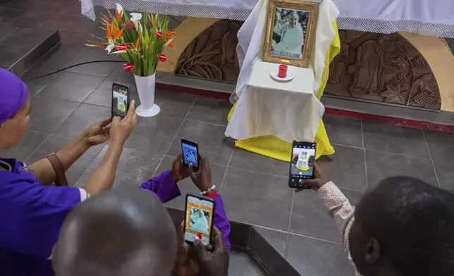 Parishioners takes pictures of the late Pope Francis' portrait after a mass at the Catholic Church in Goma, Democratic Republic of Congo, Saturday, April 26, 2025. (AP Photo/Moses Sawasawa)