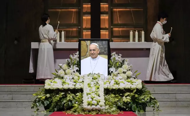 Priests prepare for a memorial Mass for the late Pope Francis near his portrait at St. Mary's Cathedral in Tokyo, Sunday, April 27, 2025. (AP Photo/Hiro Komae, Pool)