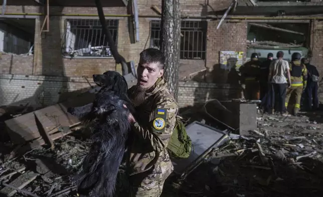 A Ukrainian serviceman carries a dog out of a house damaged by a Russian airstrike in a residential neighborhood in Kyiv, Ukraine, on Thursday, April 24, 2025. (AP Photo/Evgeniy Maloletka)