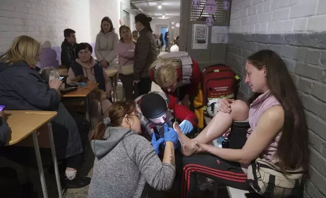 Medics treat an injured woman in a school basement being used as a shelter after a Russian airstrike on a residential neighborhood in Kyiv, Ukraine, on Thursday, April 24, 2025. (AP Photo/Evgeniy Maloletka)