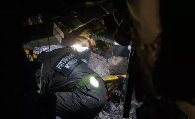 Rescue workers evacuate an injured woman from the rubble of a house destroyed by a Russian airstrike in a residential neighborhood in Kyiv, Ukraine, on Thursday, April 24, 2025. (AP Photo/Evgeniy Maloletka)