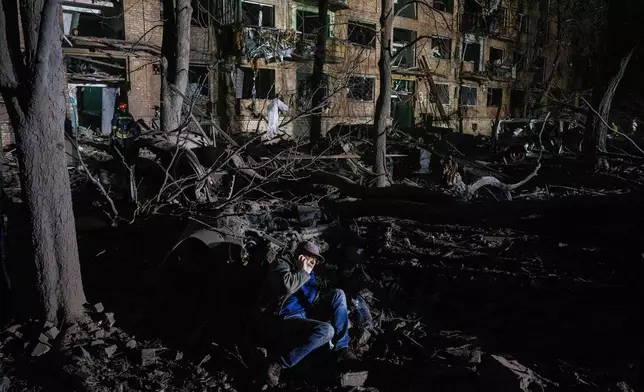 A man sits on the ground outside of a house damaged by a Russian airstrike in a residential neighborhood in Kyiv, Ukraine, on Thursday, April 24, 2025. (AP Photo/Evgeniy Maloletka)