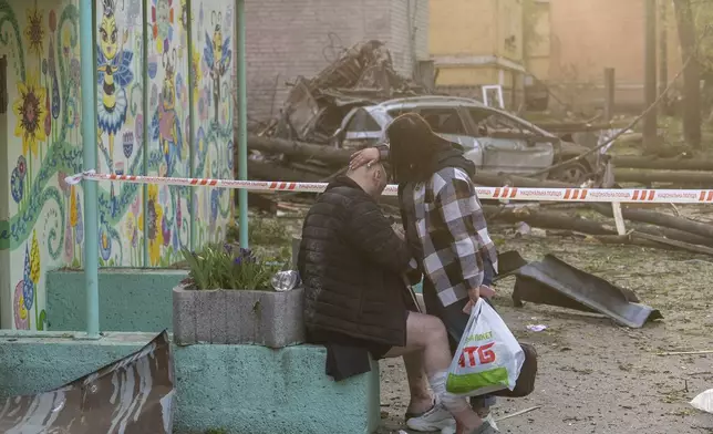 A woman helps an injured victim after a Russian strike in a residential neighborhood in Kyiv, Ukraine, Thursday, April 24, 2025. (AP Photo/Alex Babenko)