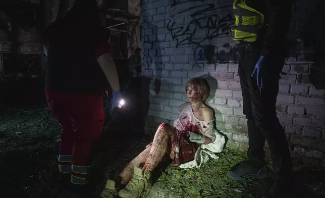 An injured woman sits near her house, which was damaged by a Russian airstrike, in a residential neighbourhood in Kyiv, Ukraine, on Thursday, April 24, 2025. (AP Photo/Evgeniy Maloletka)