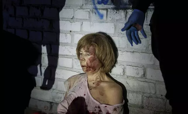 An injured woman sits near her house, which was damaged by a Russian airstrike, in a residential neighbourhood in Kyiv, Ukraine, on Thursday, April 24, 2025. (AP Photo/Evgeniy Maloletka)