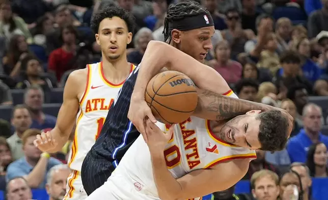Orlando Magic forward Paolo Banchero, center, and Atlanta Hawks forward Georges Niang, right, battle for a deflected shot during the second half of an NBA basketball game, Tuesday, April 8, 2025, in Orlando, Fla. (AP Photo/John Raoux)