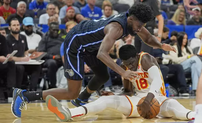 Atlanta Hawks forward Mouhamed Gueye (18) and Orlando Magic forward Jonathan Isaac, left, battle for a loose ball during the second half of an NBA basketball game, Tuesday, April 8, 2025, in Orlando, Fla. (AP Photo/John Raoux)