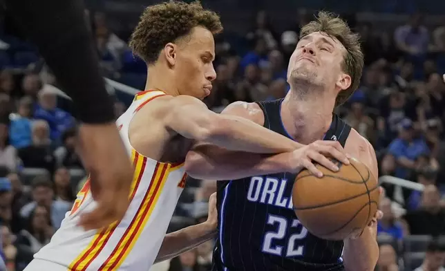 Atlanta Hawks guard Dyson Daniels, left, fouls Orlando Magic forward Franz Wagner (22) as he attempts a shot during the second half of an NBA basketball game, Tuesday, April 8, 2025, in Orlando, Fla. (AP Photo/John Raoux)