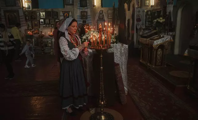 A woman lights a candle during the celebration of Orthodox Easter at St. John Theologian Church of the Orthodox Church of Ukraine in Kharkiv, Ukraine, on Sunday, April 20, 2025. (AP Photo/George Ivanchenko)