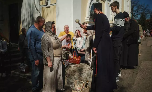 A priest blesses Easter baskets during the celebration of Orthodox Easter at Cross Lower Church of the Ukrainian Orthodox Church in Kharkiv, Ukraine, on Sunday, April 20, 2025. (AP Photo/George Ivanchenko)