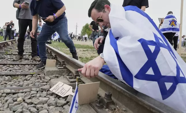 People place massages while attending the "March of the Living", the annual Holocaust remembrance event in memory of the six million Holocaust victims, at the former Nazi German death camp of Auschwitz-Birkenau in Oswiecim, Poland, Thursday, April 24, 2025. (AP Photo/Czarek Sokolowski)