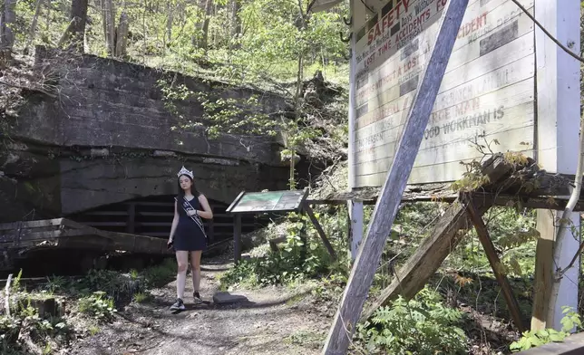 West Virginia Coal Festival teen beauty pageant winner Ava Johnson, 16, walks by a safety board at the former Kay Moor coal town and camp in the New River Gorge National Park and Preserve near Fayetteville, W.Va., Thursday, April 17, 2025, (AP Photo/Leah Willingham)