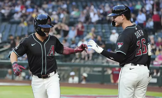 Arizona Diamondbacks' Corbin Carroll, left, celebrates his home run against the Tampa Bay Rays with Diamondbacks' Pavin Smith during the first inning of a baseball game Wednesday, April 23, 2025, in Phoenix. (AP Photo/Ross D. Franklin)