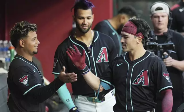 Arizona Diamondbacks' Corbin Carroll, right, celebrates his home run against the Tampa Bay Rays with Diamondbacks' Gabriel Moreno, left, as Diamondbacks' Lourdes Gurriel Jr., center, looks on during the first inning of a baseball game Wednesday, April 23, 2025, in Phoenix. (AP Photo/Ross D. Franklin)