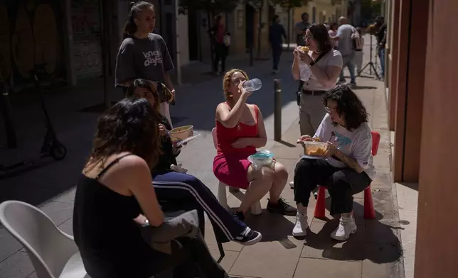 Employees of a shop have their lunch, during a major power outage in Barcelona, Spain, Monday, April 28, 2025. (AP Photo/Emilio Morenatti)